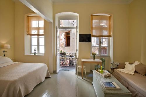 a bedroom with a bed and a couch and windows at Antica Casa Studios in Chania