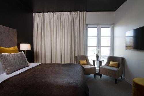 a bedroom with a bed and two chairs and a window at Wilhelmsen House in Tønsberg