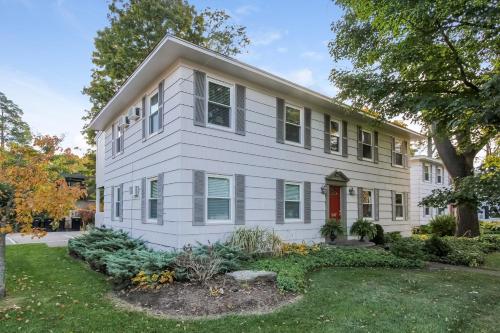 a white house with a red door and a yard at Water Street Retreat in Saugatuck