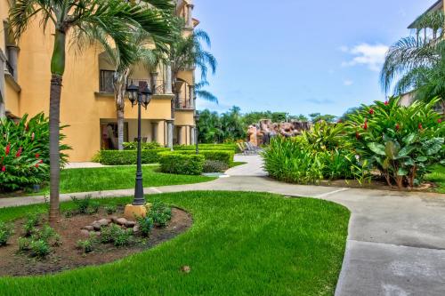 a walkway in front of a building with palm trees at Sunrise 22 in Tamarindo
