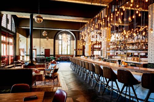 un restaurant avec un bar doté de chaises et de lustres dans l'établissement Detroit Foundation Hotel, à Detroit