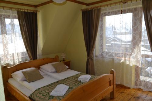 a bedroom with a bed and two windows at Durda in Poronin