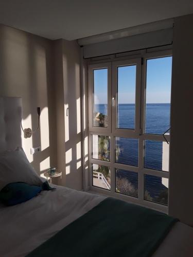 a bedroom with a large window looking out at the ocean at Apartamento Panorama 180º in Altea