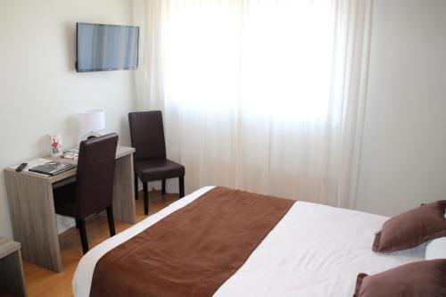 a bedroom with a bed and a desk and a television at Hôtel Saint-Hubert in Saint-Claude