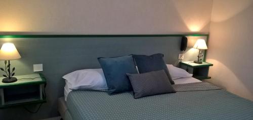 a bedroom with a bed with blue pillows and two lamps at ALIOS Hôtel Restaurant in Bas-Mauco