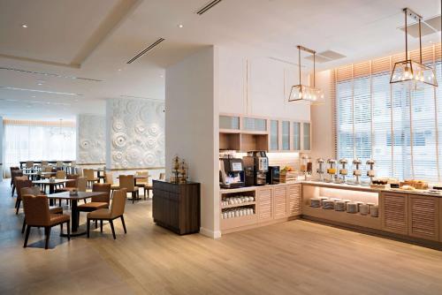 a dining room with tables and chairs and a kitchen at Hyatt Place Bangkok Sukhumvit 24 in Bangkok