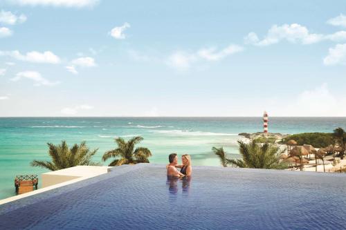 a couple sitting in a infinity pool overlooking the ocean at Hyatt Ziva Cancun in Cancún