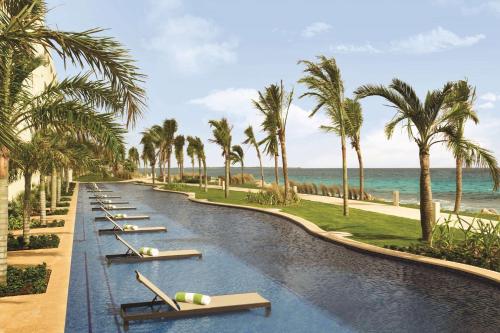 a resort pool with chaise lounges and palm trees at Hyatt Ziva Cancun in Cancún
