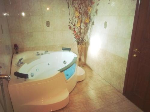 a bathroom with a tub and a vase with flowers at Guesthouse Platon in Órma