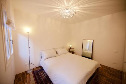 una camera con letto bianco e lampadario pendente di piccola corte a Venezia