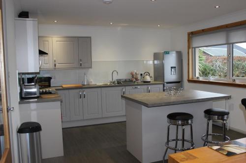 a kitchen with white cabinets and a counter with bar stools at Stroma in Portree