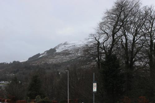 una montaña cubierta de nieve con árboles y un letrero de la calle en Stroma, en Portree