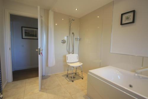 a bathroom with a shower and a chair next to a tub at Anniston Farm Cottages in Inverbervie