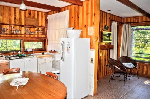 a kitchen with a table and a white refrigerator at Cabañas en Alojamientos Techo Azul in Malalcahuello