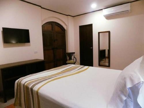a bedroom with a white bed and a television at Hotel La Recolección in León