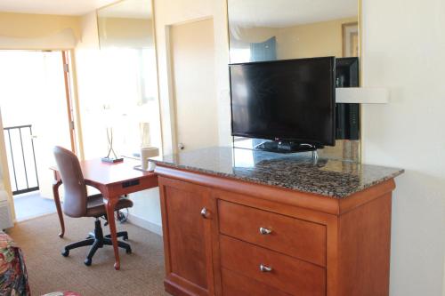 a hotel room with a desk and a television on a dresser at Grand Prix Motel Beach Front in Daytona Beach