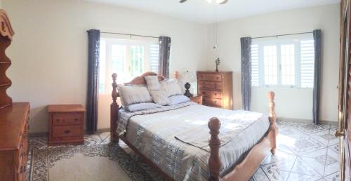 a bedroom with a bed and a dresser and two windows at Queen Quarters USVI in Christiansted