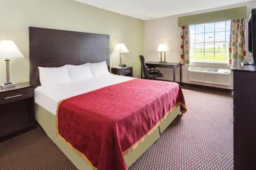 ein Hotelzimmer mit einem großen Bett und einem Fenster in der Unterkunft Baymont by Wyndham Beloit in Beloit
