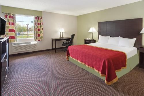 a hotel room with a large bed and a window at Baymont by Wyndham Beloit in Beloit
