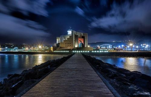a building with a boardwalk leading to the water at night at RK City Center in Las Palmas de Gran Canaria