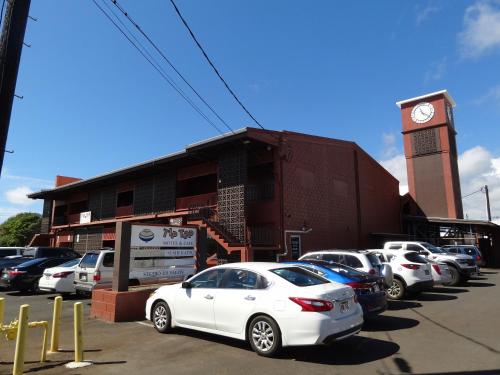 a group of cars parked in a parking lot with a clock tower at Tip Top Motel in Lihue