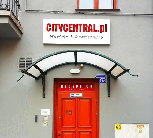 a red door on a building with a sign above it at City Central Hostel - Pokoje prywatne in Wrocław