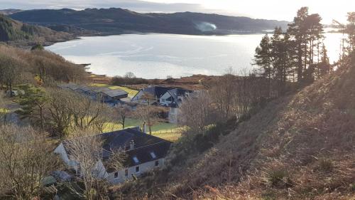 a group of houses on a hill next to a lake at The Old Cottage in Arduaine