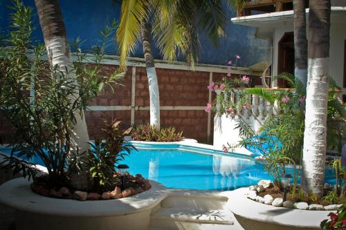 a swimming pool with palm trees in a resort at Hotel Gilda in Coyuca