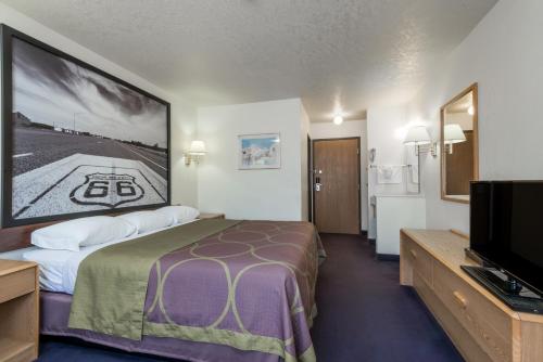 a hotel room with a bed and a flat screen tv at Super 8 by Wyndham Bernalillo in Bernalillo