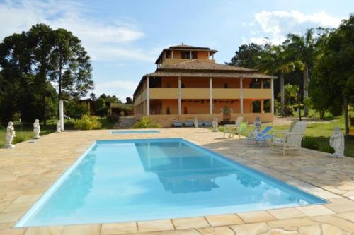 uma grande piscina em frente a uma casa em Fazenda Pousada Cachoeira do Flávio em São Tomé das Letras