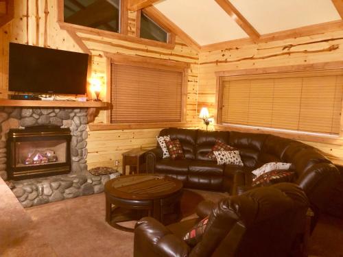 a living room with a leather couch and a fireplace at Giant Oaks Lodge in Running Springs