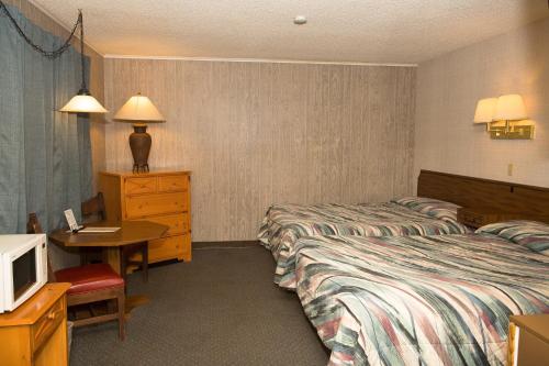 Habitación de hotel con 2 camas, escritorio y TV. en Z Bar Motel en Buffalo