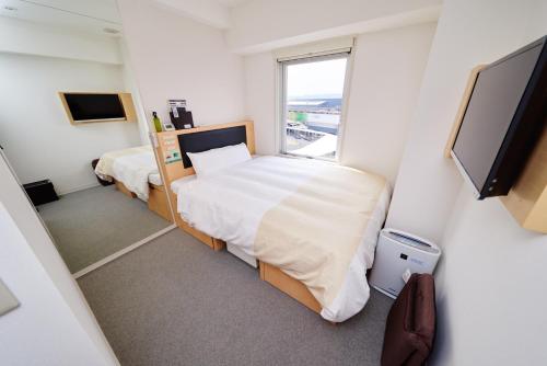 a small bedroom with two beds and a flat screen tv at Super Hotel JR Nara Ekimae Sanjo Dori in Nara