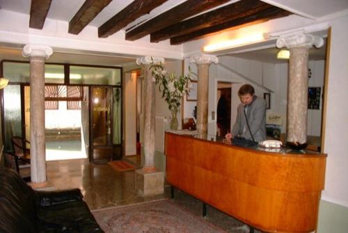 Un uomo in piedi in un bar nella hall di Hotel Caneva a Venezia