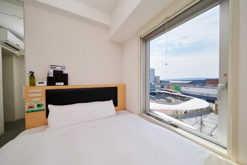 a bedroom with a bed and a large window at Super Hotel JR Nara Ekimae Sanjo Dori in Nara