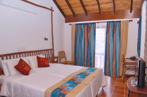 a bedroom with a bed and a television in it at Kadambavanam Ethnic Village Resort in Pālamedu