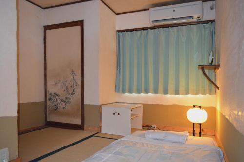 a bedroom with a bed and a window and a lamp at Guesthouse Bon in Kyoto