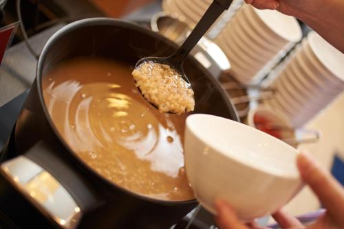 a person is stirring a pot with a spoon at Super Hotel JR Nara Ekimae Sanjo Dori in Nara