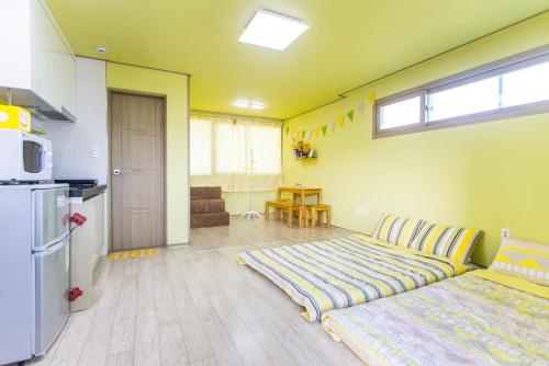 een woonkamer met een bed en een keuken bij 6pm Pension in Jeju-stad