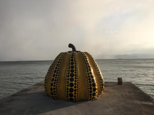 a large yellow sculpture sitting on a pier near the water at Naoshima Backpackers Guesthouse in Naoshima