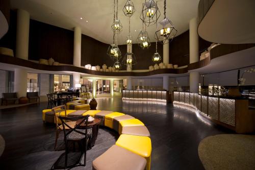 a bar with yellow and white benches and tables at Bali Paragon Resort Hotel in Jimbaran