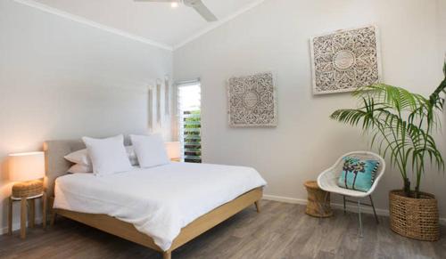 um quarto com uma cama branca e um vaso de plantas em Sols Place Boutique Pool Villas em Kalbarri