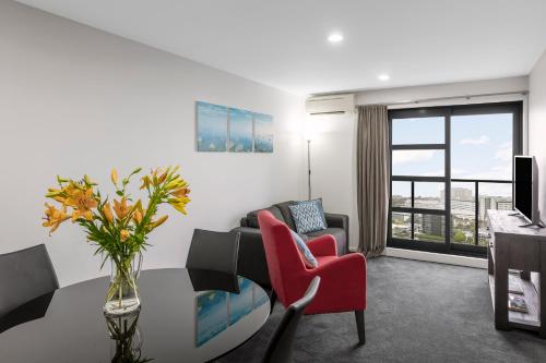 a living room with a table and red chairs at Nesuto St Martins Apartment Hotel in Auckland