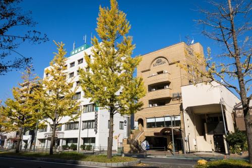 a building with trees in front of it at Hotel Sun Garden Matsuyama in Matsuyama