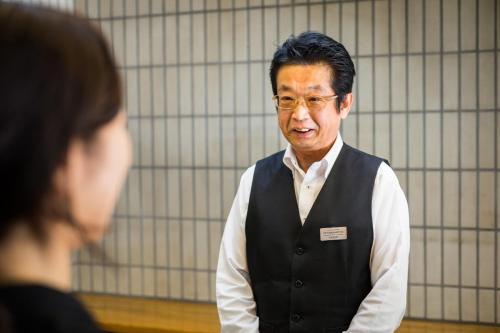 a man in a vest is talking to a woman at Hotel Sun Garden Matsuyama in Matsuyama