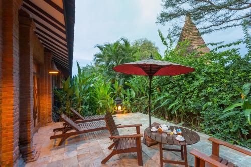 a patio with a table and chairs and an umbrella at The Hotel @ Tharabar Gate in Bagan