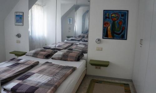 a room with three beds in it with a painting on the wall at BodenSEE Apartment 1 - 4 Daisendorf bei Meersburg in Daisendorf