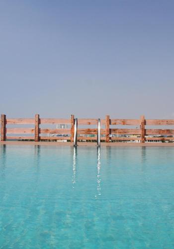 a pool of blue water with a wooden fence at Coza Ceylon in Mount Lavinia