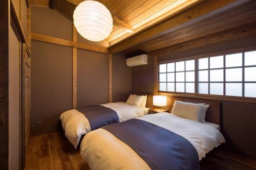 a bedroom with two beds in a room with a window at Bonbori an Machiya House in Kyoto