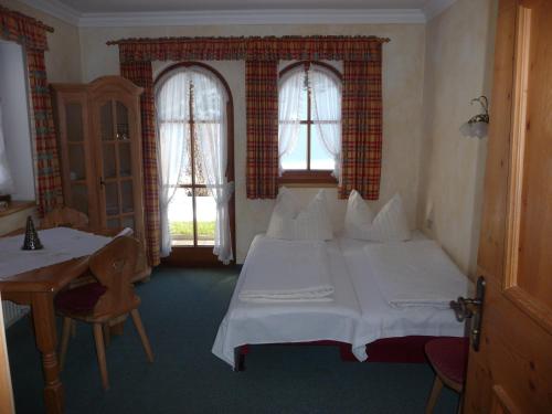 a bedroom with a white bed and two windows at Landhaus Maria in Finkenberg